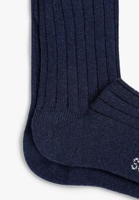 Calcetines azul marino acanalados hechos de material de punto texturizado, con un talón y puntera reforzados, y un pequeño logo blanco en el lateral.