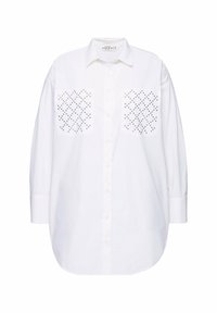 Camicia bianca a maniche lunghe in cotone con colletto, caratterizzata da due tasche decorative con motivi a pois neri e chiusura con bottoni.