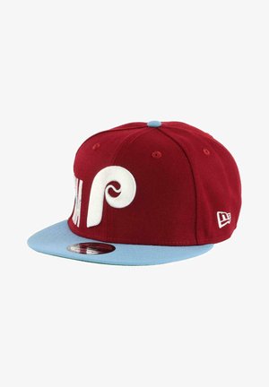 Red cap with a light blue flat brim, featuring white embroidered logo and accents, made of fabric with a smooth texture.