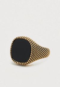 Δαχτυλίδι σε χρυσό τόνο με στρογγυλεμένη ταινία και μαύρο τετράγωνο κεντρικό λίθο, υφασμένο με μικρές σφαιρικές λεπτομέρειες γύρω από την άκρη.