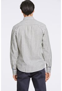 Camisa a rayas con líneas verticales verdes y blancas, cuello con botones y puños a rayas en contraste. Tejido suave con un corte estructurado.