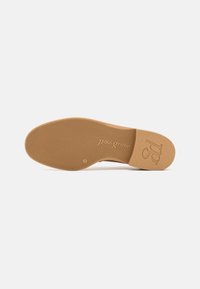 Tan schoenen met een loopzool met een gestructureerd oppervlak, een reliëflogo en een ronde hiel. Vlakke, gladde constructie ontworpen voor stabiliteit en grip.