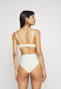 Set di lingerie verde chiaro caratterizzato da un tessuto morbido, sottili spalline, chiusura a gancio regolabile sul retro e design a vita alta.
