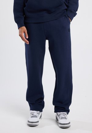 Marineblauwe trainingsbroek van zacht, dik materiaal, met een trekkoord in de taille, zijzakken en een klein logo op de linkerheup.