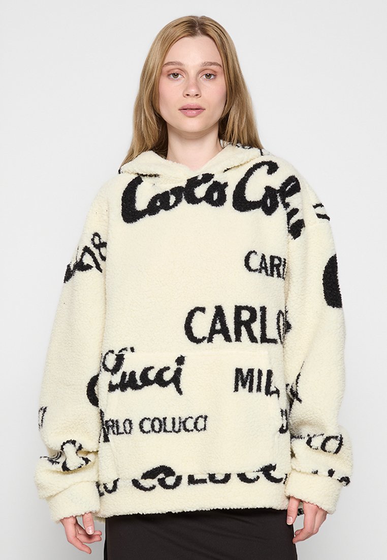 Fleece-Hoody in Creme mit schwarzen Logos. Merkmale sind eine große frontale Tasche, ein übergroßes Design mit Kapuze und abgesenkten Schultern.