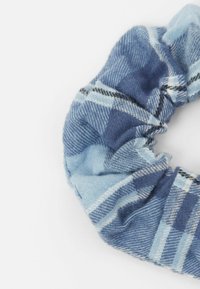 Modrý kostkovaný gumička do vlasů vyrobená z měkké tkaniny s různými odstíny modré a bílými pruhy. Texturovaná s nařaseným designem.