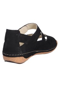 Zwarte suède schoen met uitsnijdingen, kurken zool en contrasterende stiksels. Heeft een lage hak en een open achterkant voor eenvoudig aan- en uittrekken.