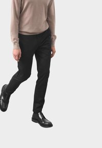 Czarne spodnie wizytowe o slim fit, w połączeniu z jasnobe�żowym swetrem. Spodnie mają gładką fakturę, a całość dopełniają błyszczące czarne buty.