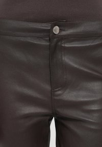 Pantaloni negri din piele ecologică cu o textură netedă, având un buzunar frontal, închidere cu buton metalic și detalii de cusături subtile.