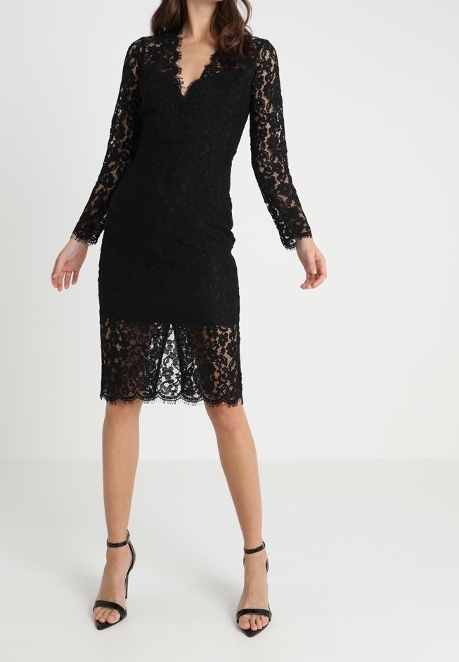 Musta pitsimekko pitkilla hihoilla, V-pääntiellä ja polvi-pituisena, jossa on aallotuksella viimeistelty reuna ja vartalonmyötäinen siluetti.