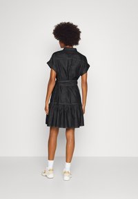 Denim dress with short sleeves, fitted bodice, and flowing skirt. Features a belted waist and a gathered hem in a dark wash.