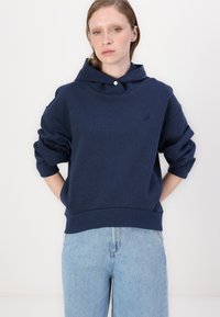 Felpa blu navy con tasca anteriore e maniche arrotolate. Materiale in cotone morbido, con un logo discreto sul petto e vestibilità comoda.