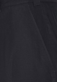 Czarne lniane spodnie o gładkiej fakturze, z ukośnymi kieszeniami z przodu i starannym przeszyciem wzdłuż szwów.