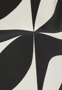 Black and white fabric featuring a large, abstract leaf pattern with smooth texture. The design contrasts bold shapes against a light background.