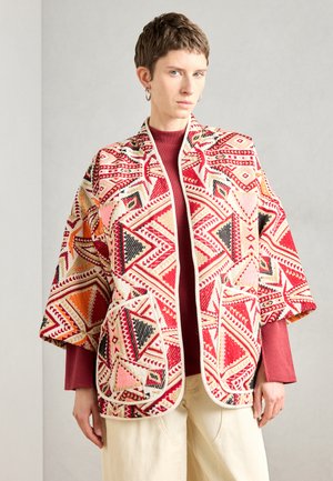 Patterned kimono jacket featuring red, pink, and black geometric designs. Made of textured fabric with open front and two front pockets.