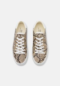Zapatillas con un diseño de estampado de serpiente en tonos beige y marrón, cordones blancos y ojales en tono dorado. Presentan una punta redondeada y una suela blanca.