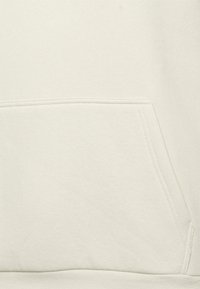 Felpa beige chiaro con tasca a marsupio, texture liscia e orlo a costine. Cuciture chiare lungo la tasca e le cuciture.