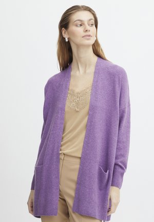 Cardigan mov din material moale, cu un design deschis în față și două buzunare frontale. Purtați peste un top bej, cu mâneci lungi.