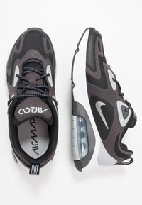 Černé a šedé atletické tenisky s vrchní částí z prodyšné síťoviny a syntetického materiálu, polstrovanou podrážkou, viditelnou vzduchovou jednotkou a výraznými bílými a stříbrnými detaily.