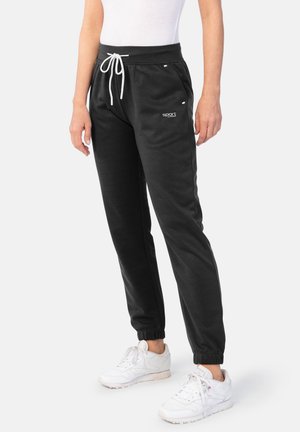 Schwarze Jogginghose mit elastischen Bündchen, Kordelzug-Taille und seitlichen Akzenten. Weißes Logo am Oberschenkel und kontrastierender weißer Kordelzug. Glatte Textur.