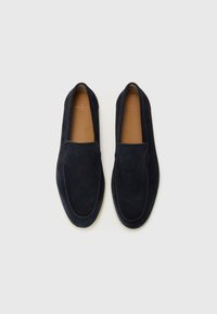 Marinblå mockaloafers med platt sula, slip-on-design och synlig sömdetalj runt den övre kanten. Slät läderinnersula.