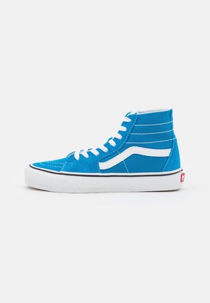 Baskets montantes bleues avec lacets blancs, bande latérale blanche et semelle blanche épaisse avec bordure noire sur fond uni.