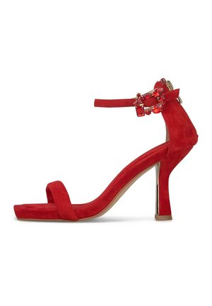 Czerwona zamszowa sandałka na wysokim obcasie typu słupek, z paskiem na przodzie i paskiem wokół kostki ozdobionym dekoracyjną klamrą z biżuterią.