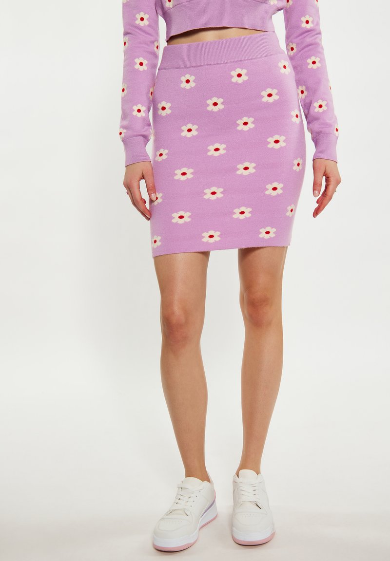 Fustă tricotată liliachie cu un model floral în alb și roșu, având un design ajustat și un tiv ondulat. Asortată cu adidași albi.