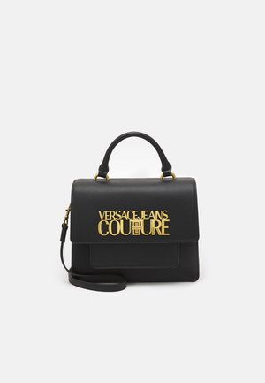 Czarna skórzana torebka z górnym uchwytem i odpinanym paskiem na ramię, ozdobiona złotym logo "Versace Jeans Couture" na przednim klapie.