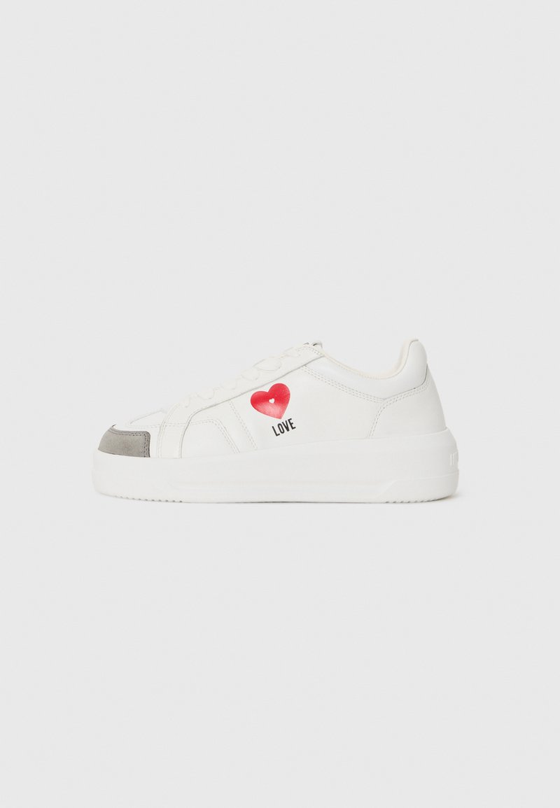 White sneakers with a smooth leather finish, featuring a red heart graphic and the word "LOVE," grey suede toe cap, and rubber sole.