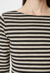 Top a righe nere e beige con scollo ampio e maniche a tre quarti, realizzato in un tessuto liscio ed elastico.