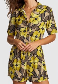 Robe à manches courtes à motifs floraux dans des teintes de jaune et de marron, dotée de boutons sur le devant, d'un col et d'une coupe décontractée.