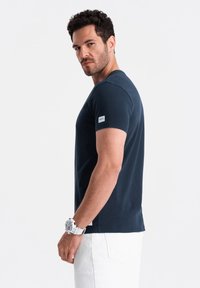 Navy blue short-sleeve T-shirt made of cotton, featuring a slim fit, crew neckline, and a small white label on the left sleeve.