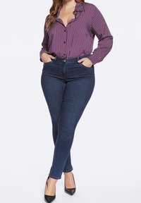 Slim fit, tmavě modré džíny v kombinaci s dlouhým rukávem, košilí na knoflíky v purpurové barvě s bílými pruhy. Má klasický límec a rovné nohavice.