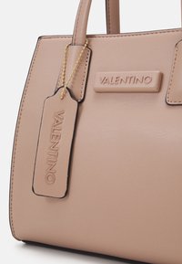 Rosa läderhandväska med strukturerad form, med en texturerad yta, guldfärgad tagg och präglad "VALENTINO"-logotyp.