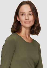 Olijfgroene langemouwen shirt met een ronde hals, gemaakt van zachte stof, met een gladde textuur en een getailleerde silhoutte.
