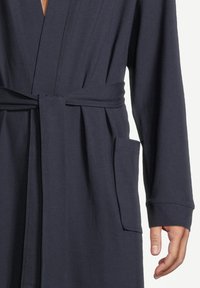 Granatowy bawełniany szlafrok z paskiem w talii, długimi rękawami i kieszonką z przodu. Gładka faktura i luźny krój, z kołnierzem w stylu kimono.