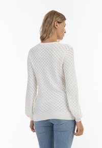Maglione leggero bianco con un motivo a diamante testurizzato, maniche lunghe e polsini e orlo a costine. La vista posteriore mostra una vestibilità rilassata.