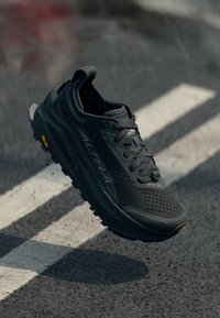 Baskets de sport noires avec une tige en mesh texturé, un système de laçage et une semelle épaisse rembourrée avec un accent Vibram.