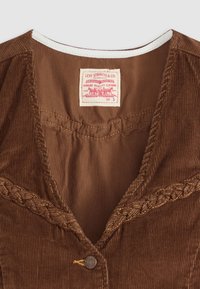 Smeđi kordura materijal s pletenim šavom duž ovratnika, s okruglim dugmetom i etiketom koja glasi "Levi Strauss & Co."