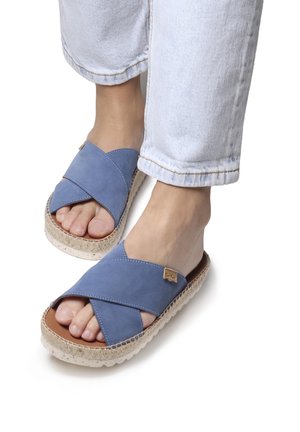 Blue leather slide sandals with crisscross straps, textured midsole, and a natural rope accent around the base. Flat sole, open-toed design.