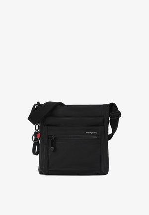 Sac bandoulière noir avec une sangle d'épaule ajustable, poche zippée à l'avant, petit logo Hedgren et porte-clés attaché avec une touche rouge.