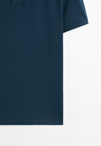 Marineblaue Kurzarm-Poloshirt-Sektion mit sichtbarem Ärmelbündchen und teilweisem Kragen vor weißem Hintergrund.