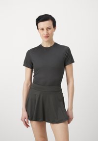 Top atlético gris oscuro de mangas cortas combinado con una falda acampanada a juego que presenta una cintura ajustada y una textura suave.