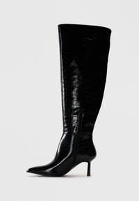 Knöchehohe schwarze Stiefel mit einer glänzenden Krokodilprägung. Spitz zulaufende Zehen und dünner Absatz; mit einem seitlichen Reißverschluss zum Verschließen.