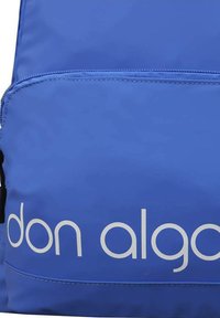 Mochila de nailon azul con un gran bolsillo frontal, una textura suave y el logo "don algodon" en blanco. Cierre de cremallera y correas reforzadas.