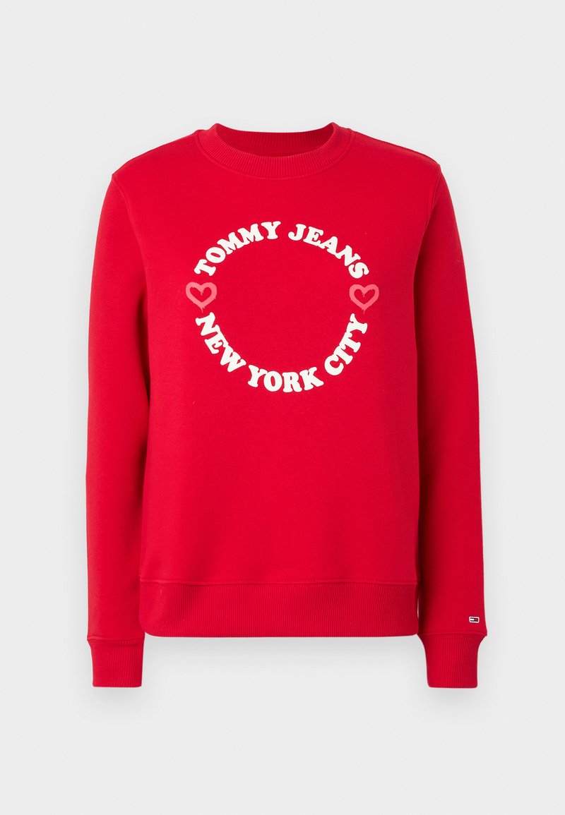 Felpa rossa con colletto e polsini a costine. Presenta un logo bianco circolare con il testo "TOMMY JEANS" e "NEW YORK CITY", accentuato da simboli a forma di cuore.