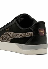 Zapatilla negra con parte superior de ante texturizado, panel lateral con estampado de leopardo, detalles plateados y suela de goma blanca. Logo de PUMA en el talón.