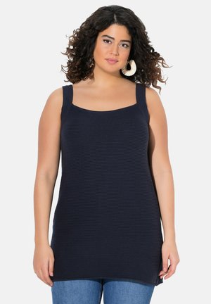 Navyblaues geripptes Tanktop mit breiten Trägern und runder Ausschnitt, kombiniert mit Jeans. Der Stoff hat eine strukturierte Oberfläche.