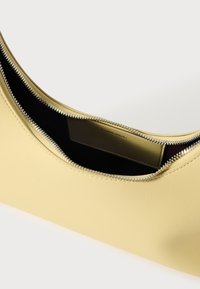 Yellow leather bag with a smooth texture and a zippered closure. Interior features a contrasting dark lining and an embossed logo.